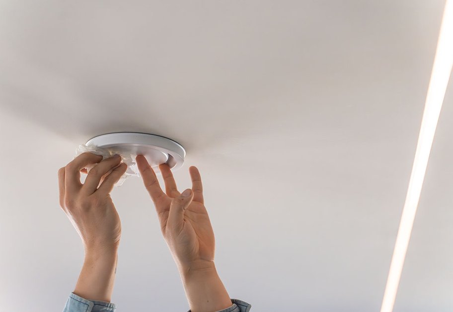Hender rengjør takmontert fraluftsventil i bolig.