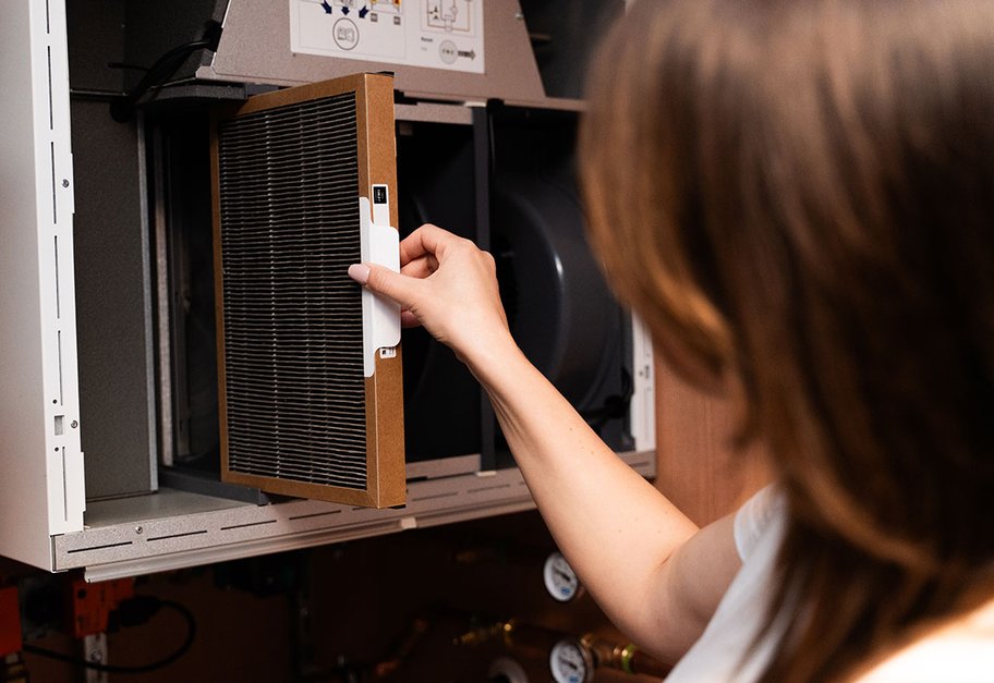 Person setter inn filter i Flexit ventilasjonsaggregat med åpnet frontdeksel.