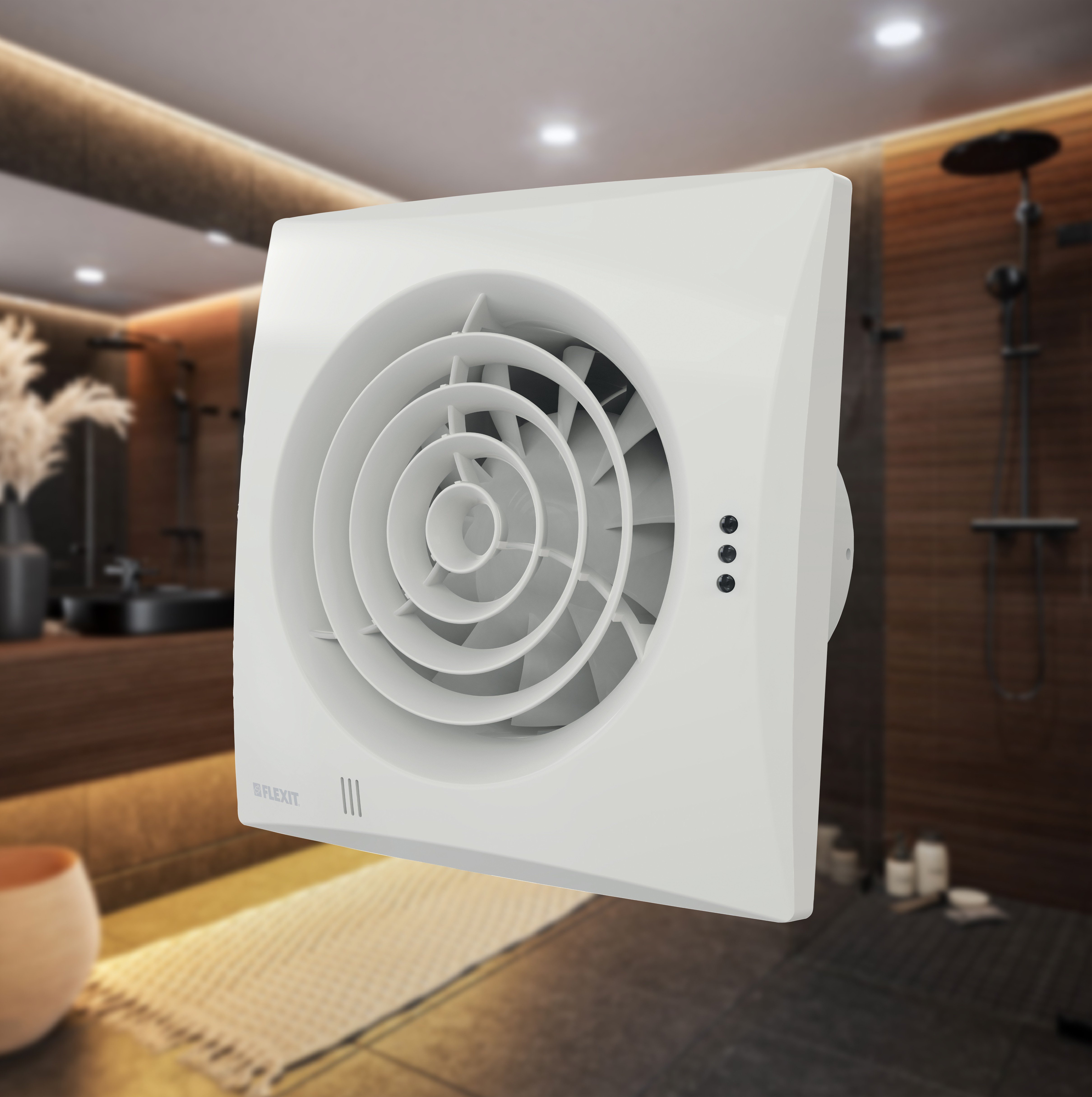 Flexit baderomsvifte med hvit front og sirkulært gitter, vist montert på vegg i baderomsmiljø.