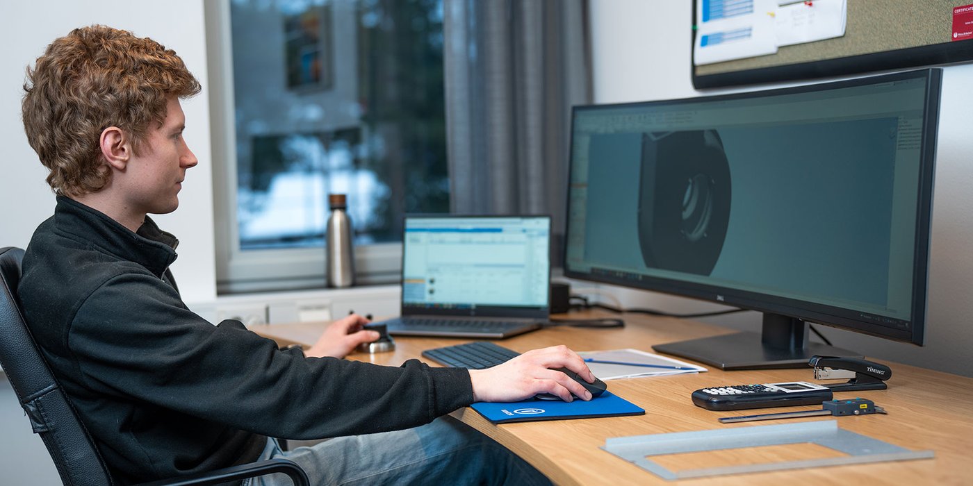 Medarbeider arbeider med digital konstruksjon av komponent på skjerm ved arbeidsplass hos Flexit.