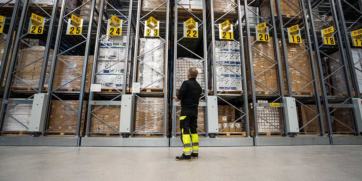 Medarbeider i høylager omgitt av pallereoler med varer, som viser Flexits logistikk og vareflyt.