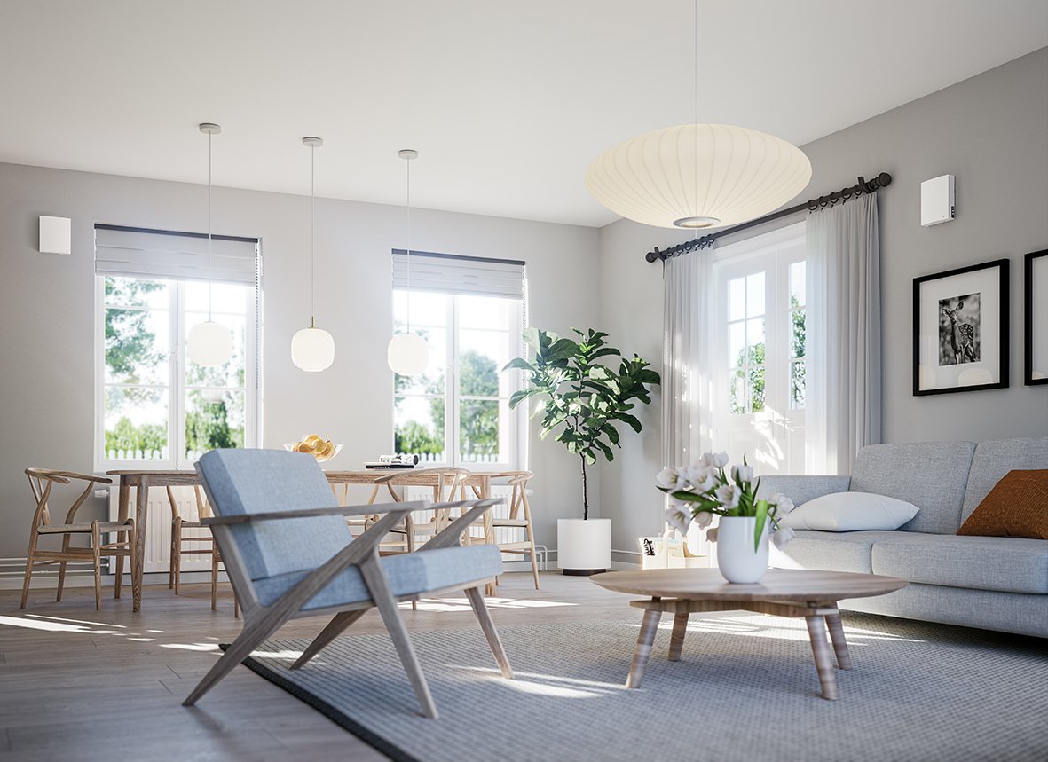 Stue og spiseplass med romventilatorer montert høyt på veggene i lyst, skandinavisk interiør