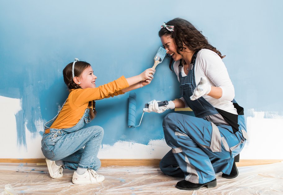 Barn og voksen som maler en vegg sammen i et godt ventilert innemiljø.