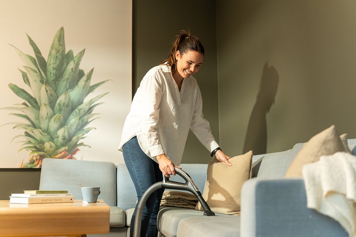 Person som støvsuger og rydder i en lys og godt ventilert stue.